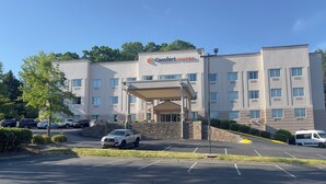 A hotel named 'Comfort Suites' with a covered entrance, parking lot, and a stone wall.