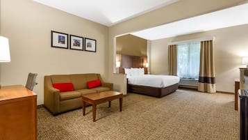 A hotel room with a bed, a sofa, a desk, and a carpeted floor.