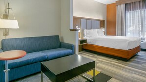 Een hotelkamer met een bed, een slaapbank, een tafel en een lamp.