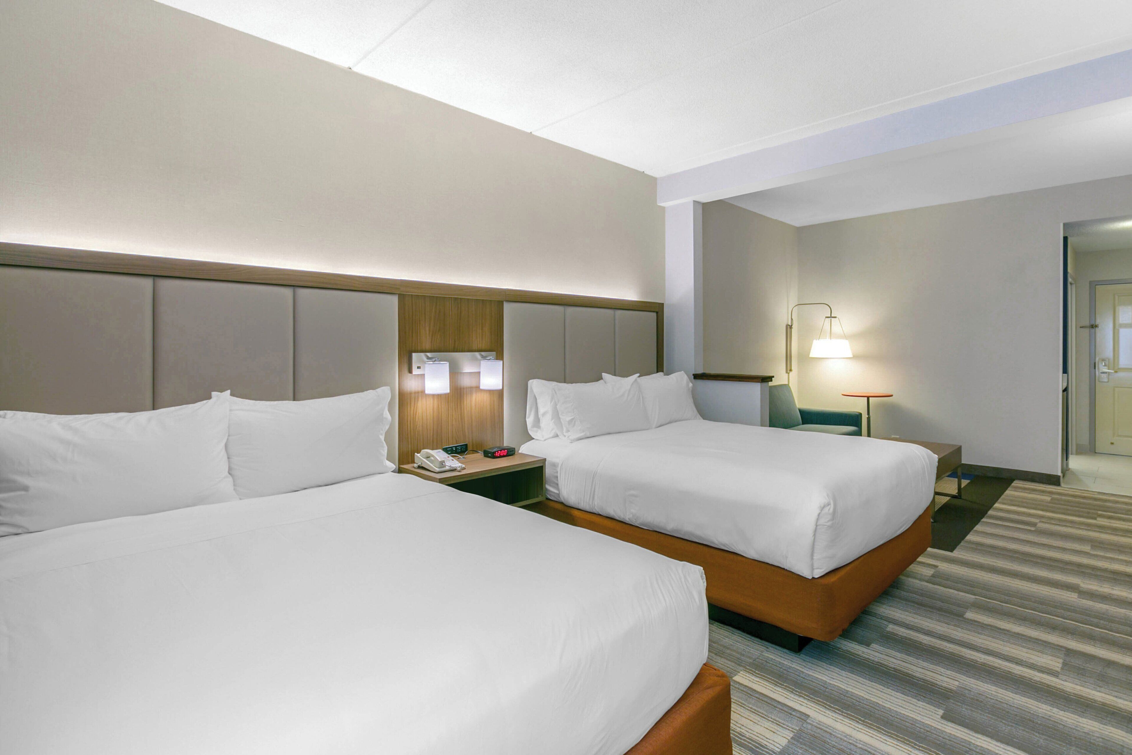 Habitación de hotel con dos camas, una mesita de noche con un teléfono y una lámpara.