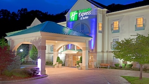A Holiday Inn Express & Suites building with a covered entrance, landscaped garden, and a clear sign indicating the hotel's name.