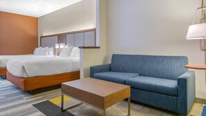 Een hotelkamer met een bed, een bank, een klein tafeltje en een lamp.