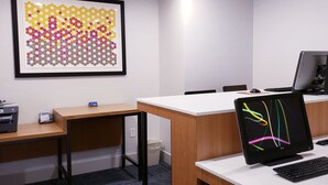Un espacio de oficina moderno con un escritorio, impresora, monitor de computadora y una obra de arte abstracta enmarcada en la pared.