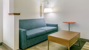Una habitación con un sofá azul, una mesa de madera y una lámpara en la pared.