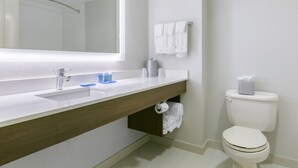Een moderne badkamer met een witte wastafel, spiegel en toilet.