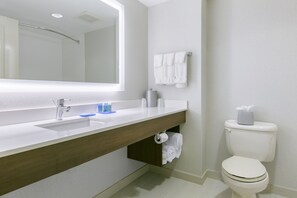 A modern bathroom with a white sink, mirror, and toilet.