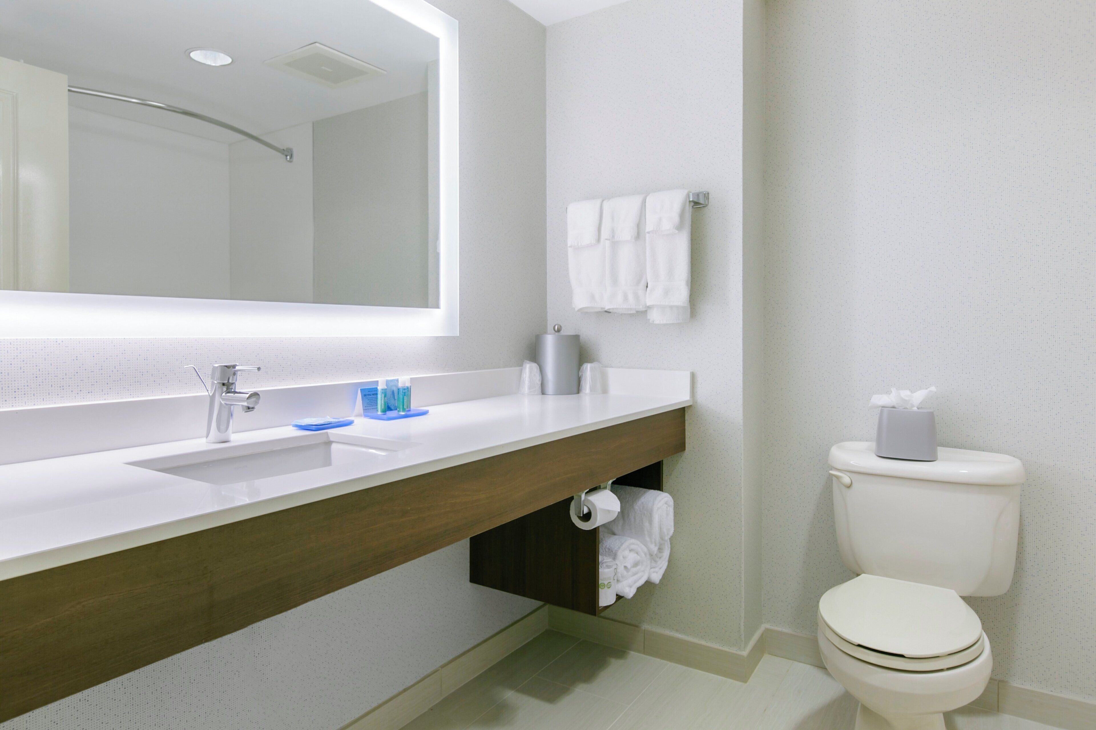 A bathroom with a white sink, mirror, and toilet.