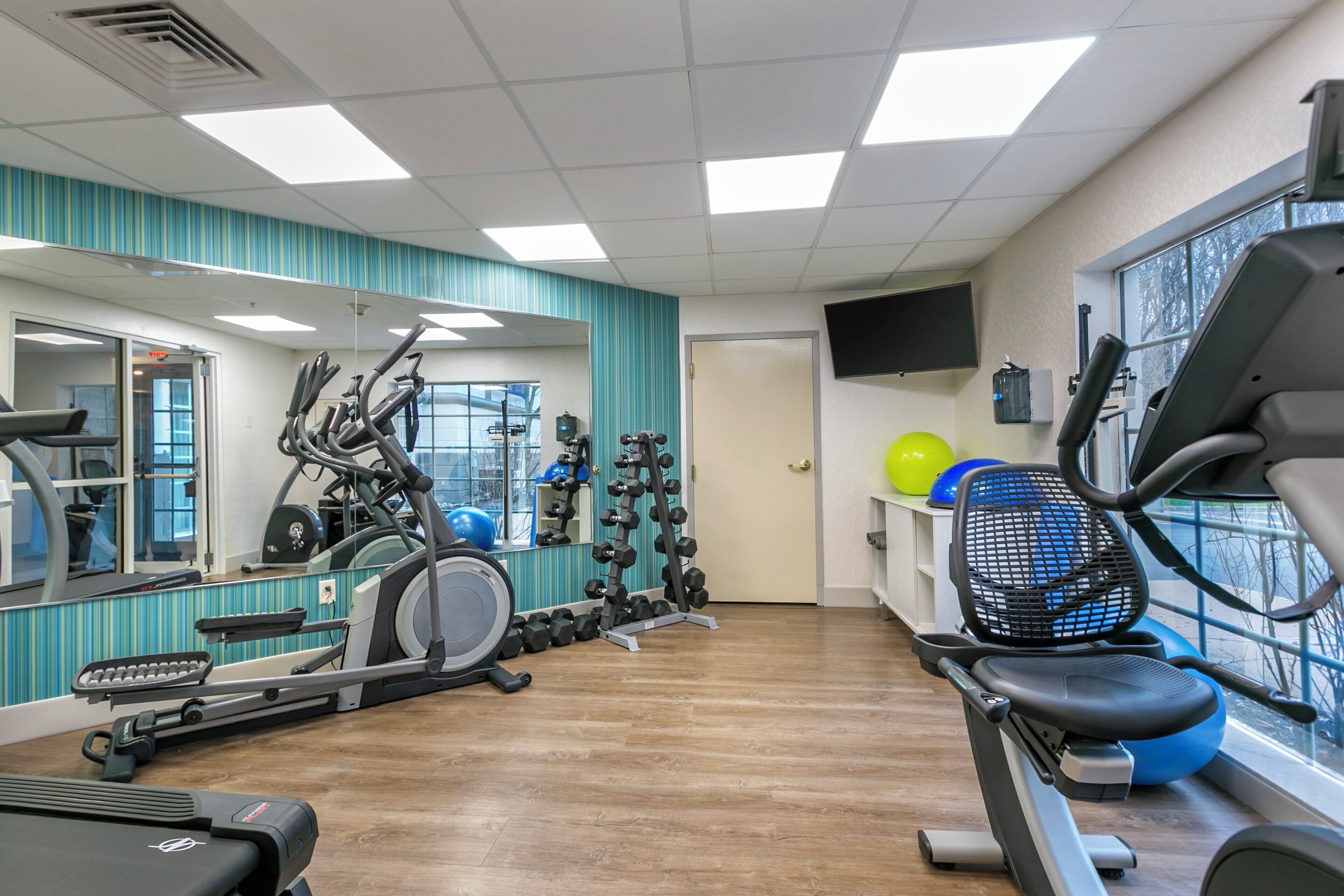 A gym with exercise equipment, a mirror, and a window.