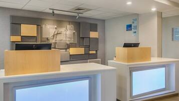A reception area with two reception desks, a wall-mounted sign, and a ceiling-mounted light fixture.