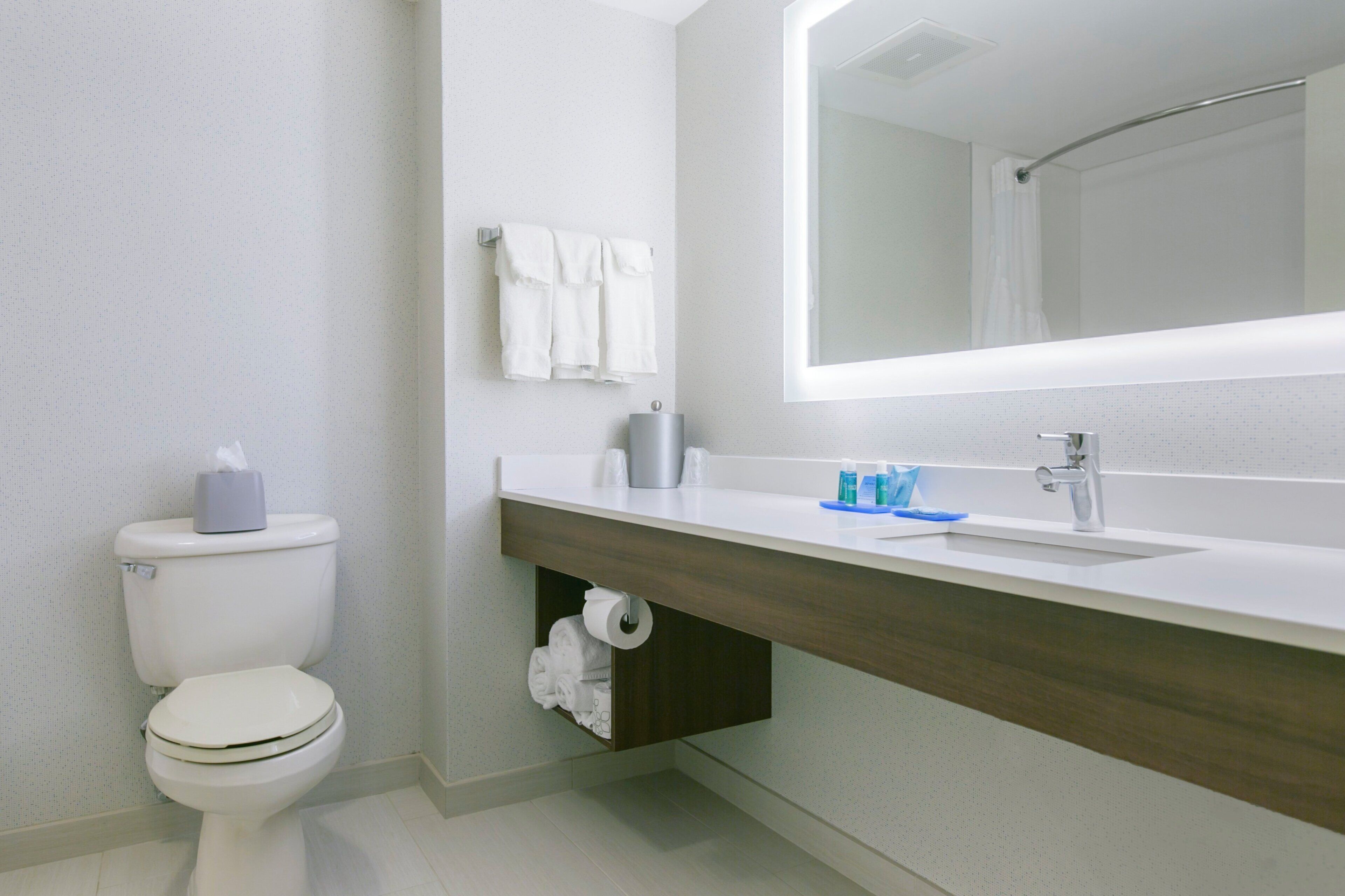 A modern bathroom with a toilet, sink, mirror, and towel rack.