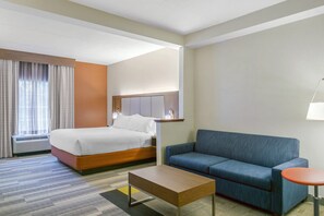 Een hotelkamer met een bed, een bank, een tafeltje en een lamp.