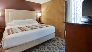 Una camera d'albergo con un letto grande, una televisione, una parete decorata con mattoni e un pavimento a motivi.