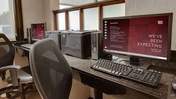 Een hotel receptiebalie met een computer, een monitor waarop een welkomstbericht staat en een stoel.