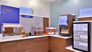 A modern kitchen with a breakfast station, including a coffee machine, a yogurt dispenser, and a sign listing breakfast items like yogurt, eggs, and milk. - Holiday Inn Express New Orleans - Arts District by IHG (New Orleans)