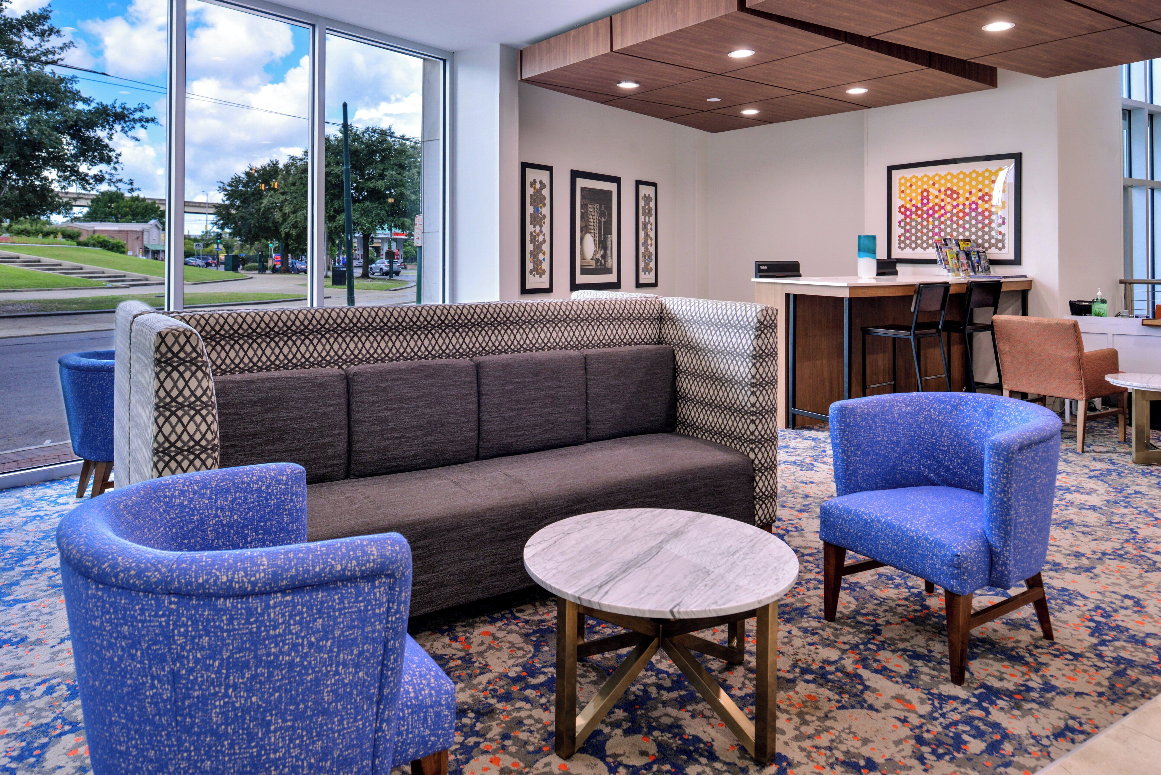 A hotel lobby with a sofa, two armchairs, a small round table, and a reception desk.