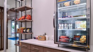 A kitchen area with a refrigerator stocked with food items, a counter with various kitchen supplies, and a view of the dining area through a glass door. - Holiday Inn Express New Orleans - Arts District by IHG (New Orleans)
