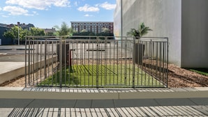A fenced outdoor area with a paved walkway, a grassy patch, and a building in the background. - Holiday Inn Express New Orleans - Arts District by IHG (New Orleans)