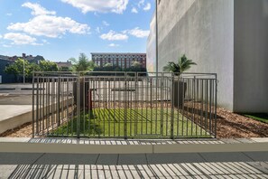A fenced outdoor area with a paved walkway, a grassy patch, and a building in the background. - Holiday Inn Express New Orleans - Arts District by IHG (New Orleans)