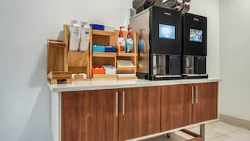 Een kitchenette met een koffieapparaat, een waterdispenser en diverse etenswaren.