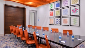 A conference room with a long table, orange chairs, and framed patterns on the wall. - Holiday Inn Express New Orleans - Arts District by IHG (New Orleans)