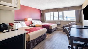 A hotel room with two beds, a desk, a chair, a TV, a coffee maker, and a window with a view.