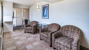 A room with two patterned armchairs, a small table, and a framed picture on the wall.