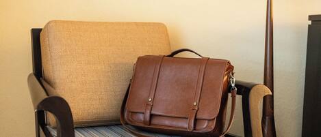 A chair with a striped cushion and a brown leather bag placed on it.