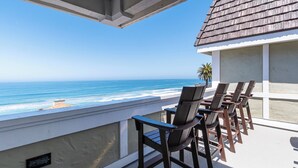 A balcony with a view of the ocean, wooden chairs, and a palm tree. - Carlsbad Inn Beach Resort (Carlsbad)
