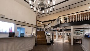 A spacious lobby with a staircase, a reception desk, and a chandelier. - Carlsbad Inn Beach Resort (Carlsbad)