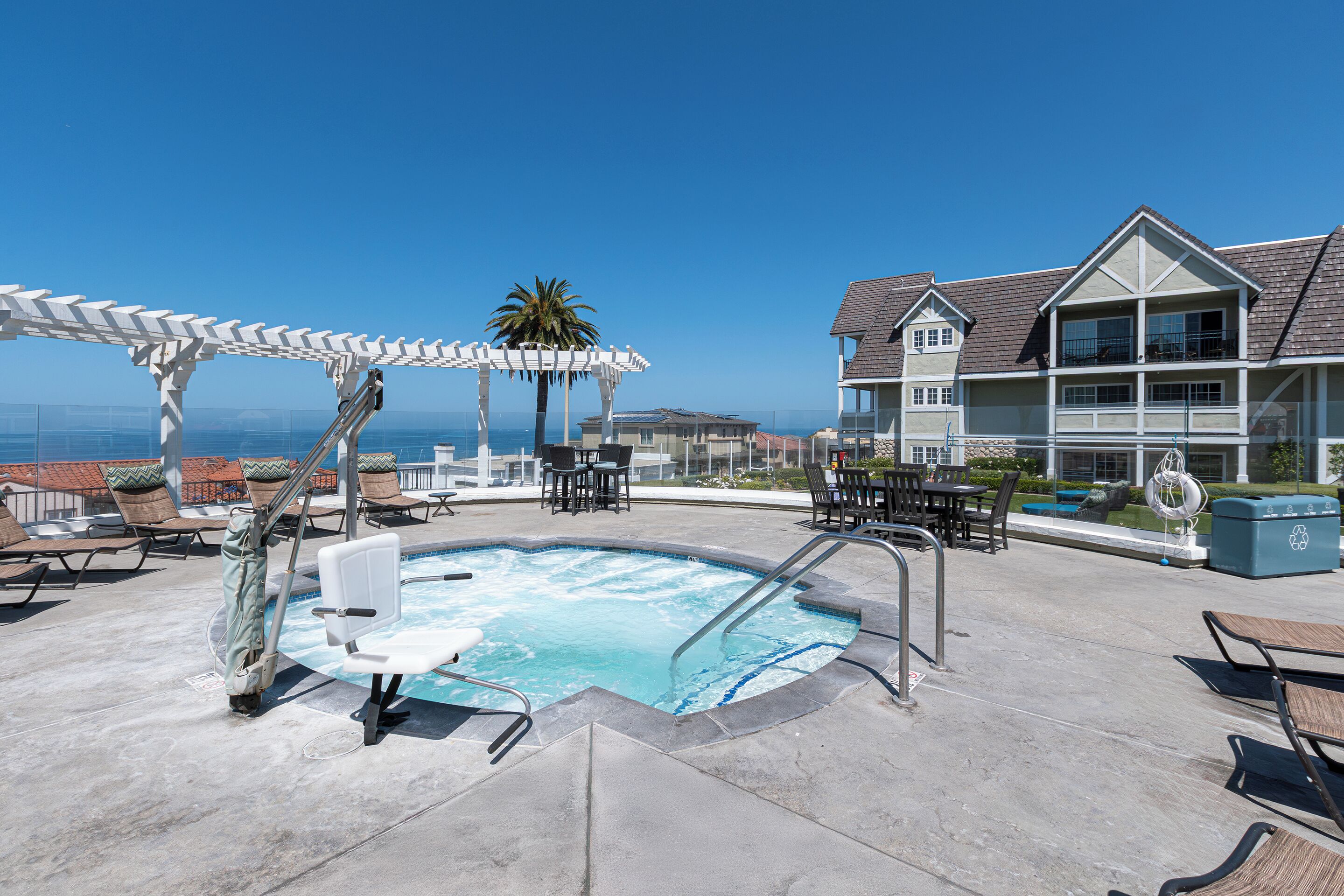 Un espace piscine aménagé sur le toit, comprenant un jacuzzi, des chaises longues et une pergola.