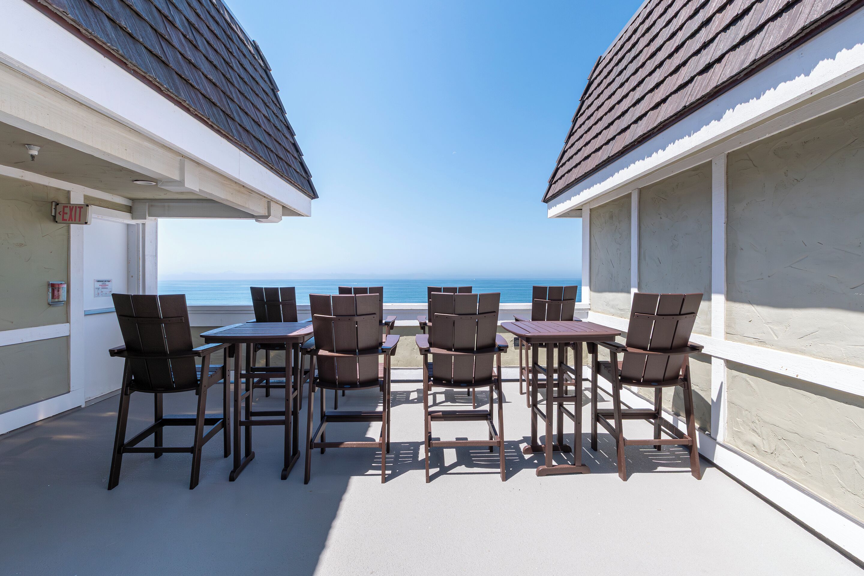 A balcony with a table and chairs, overlooking the sea.
