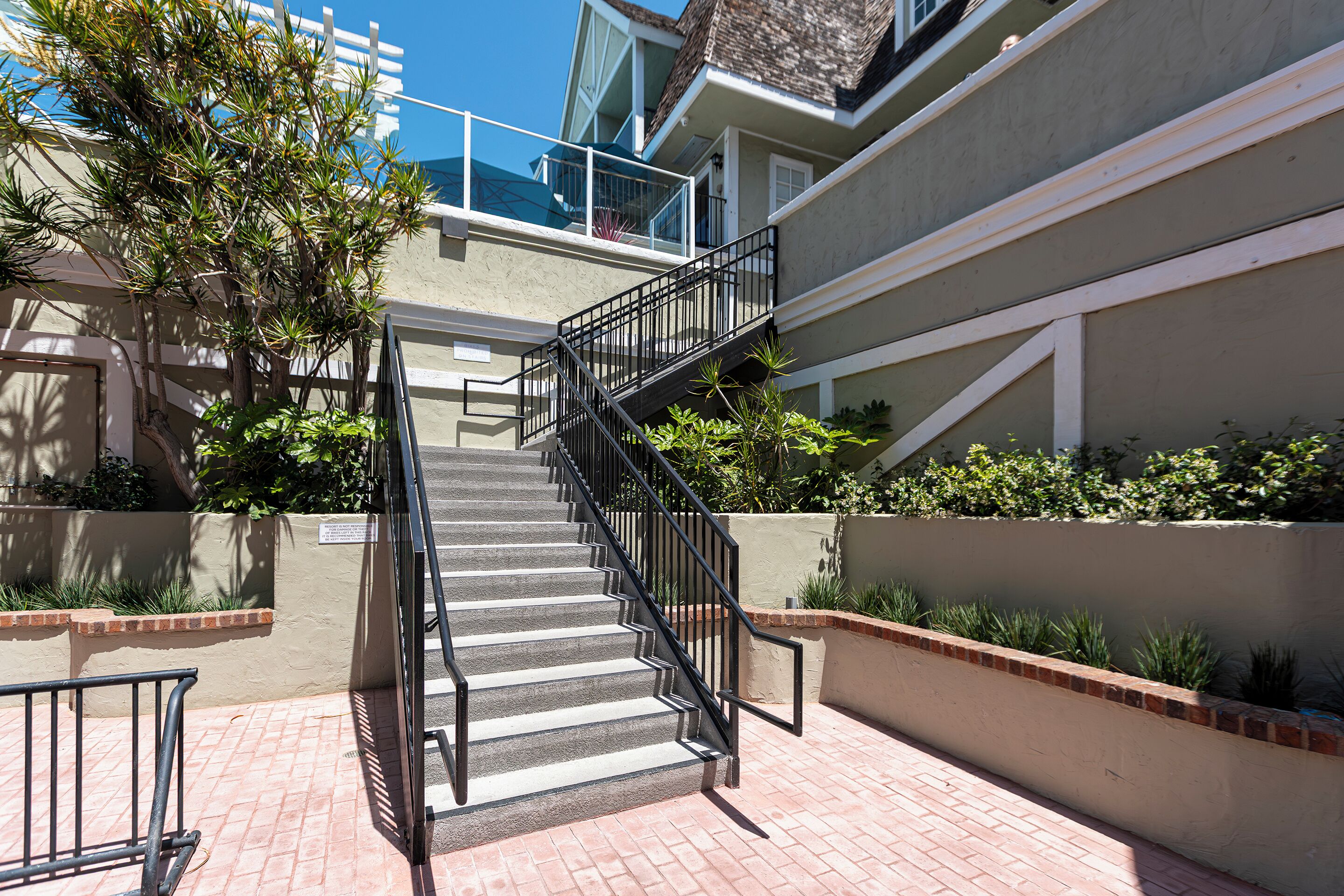 A staircase leading to a residential building with a balcony and a view of the sky.