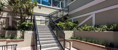 A staircase leading to a residential building with a balcony and a view of the sky.
