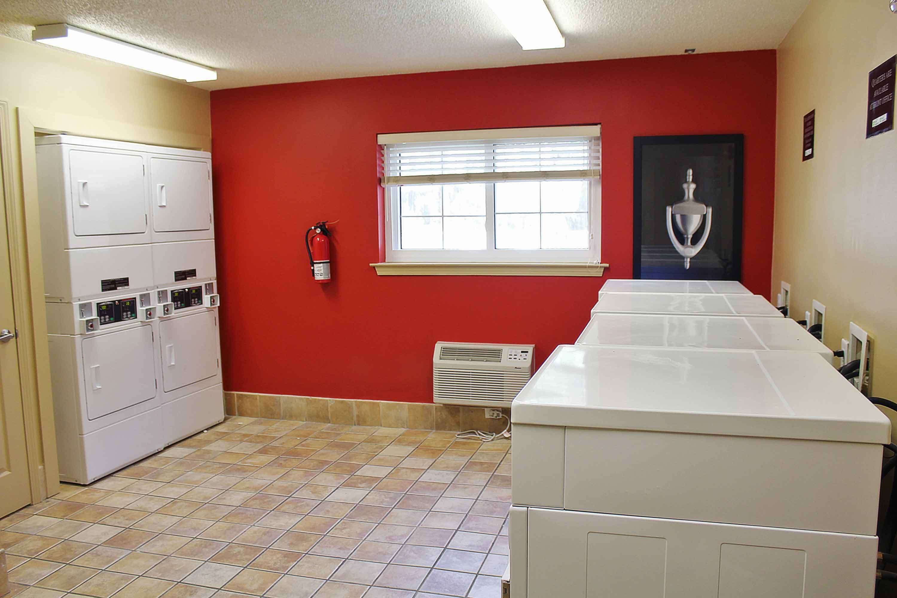 A laundry room with a red wall, a window, and a white washing machine.