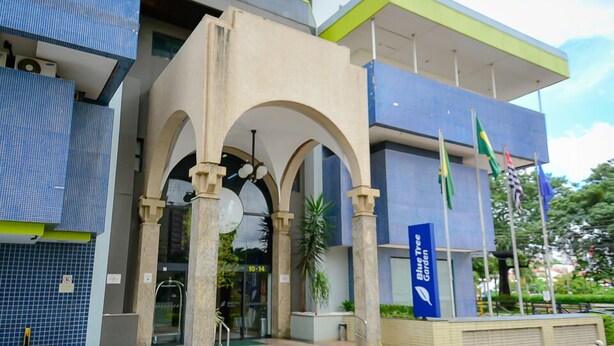 Un edificio moderno con fachada azul y color beige, que presenta una entrada destacada con arcos y un letrero que indica Blue Tree Garden.