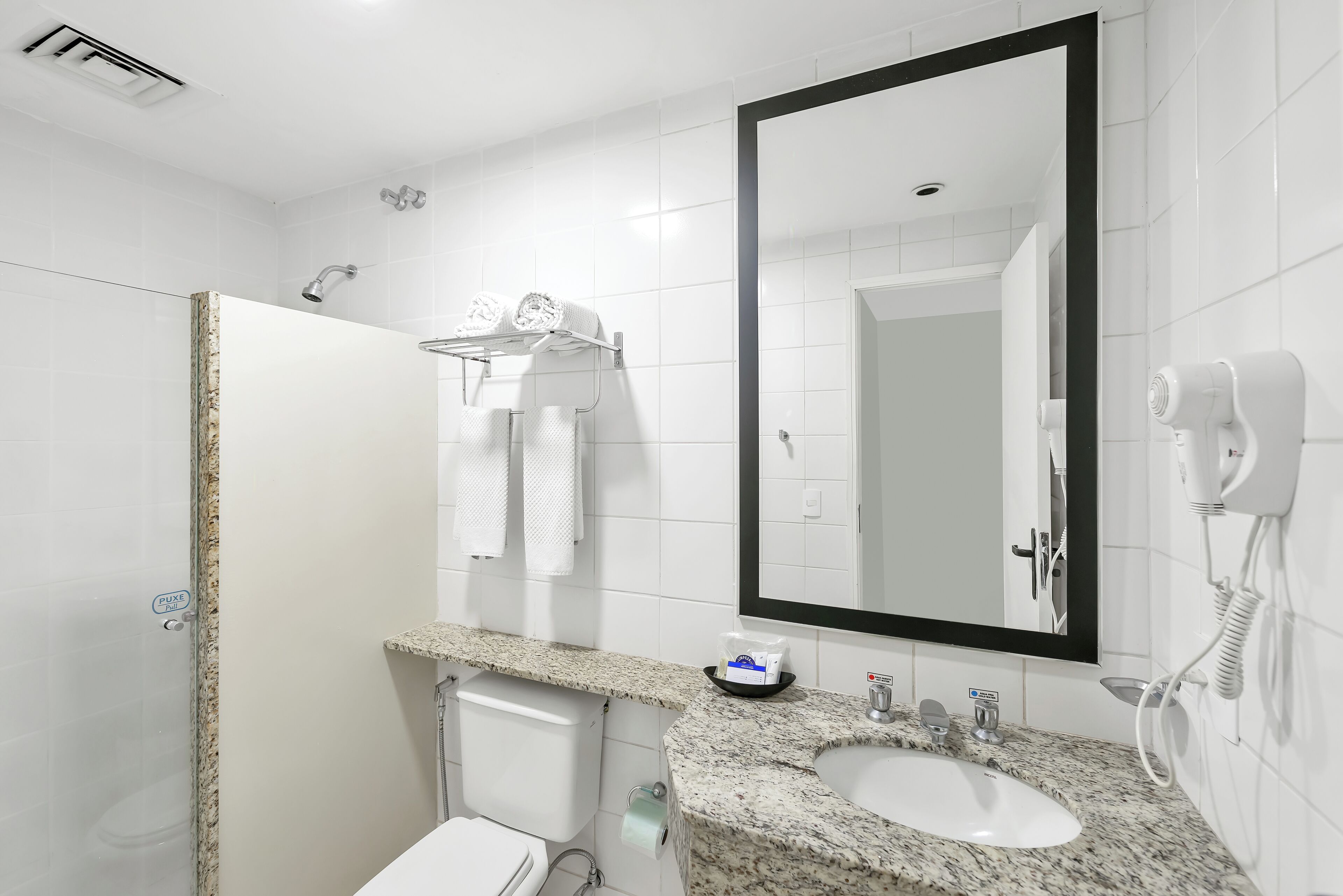 A bathroom with a white sink, a mirror, a hairdryer, and a towel rack.