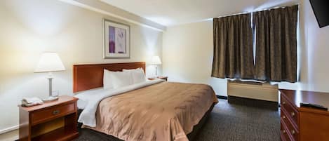 Habitación de hotel con cama, lámparas de noche, mesita de noche, cómoda, televisor de pantalla plana y ventana con cortinas.