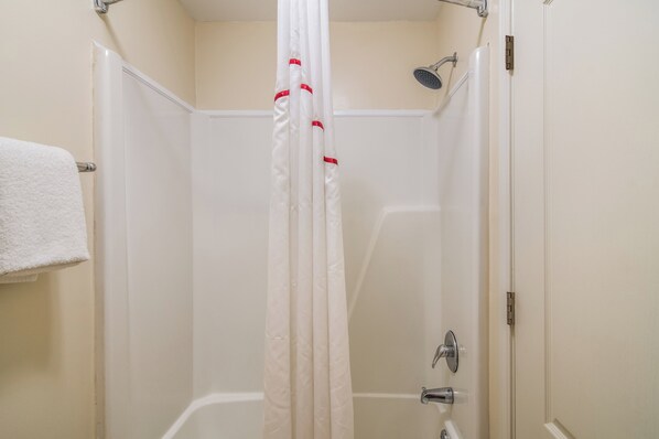 A bathroom with a shower, a bathtub, and a towel rack.