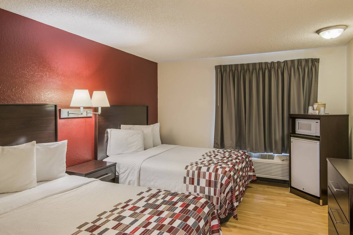 Habitación de hotel con dos camas, un escritorio, microondas y televisor.
