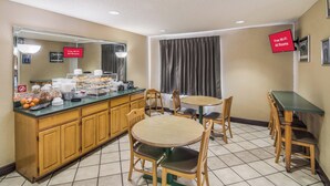 A hotel room with a kitchenette, breakfast bar, and a dining area with a table and chairs. - Red Roof Inn & Suites Pensacola East - Milton (Milton)