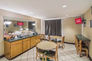 A hotel room with a breakfast bar, wooden cabinets, and a dining area with a round table and chairs. - Red Roof Inn & Suites Pensacola East - Milton (Milton)