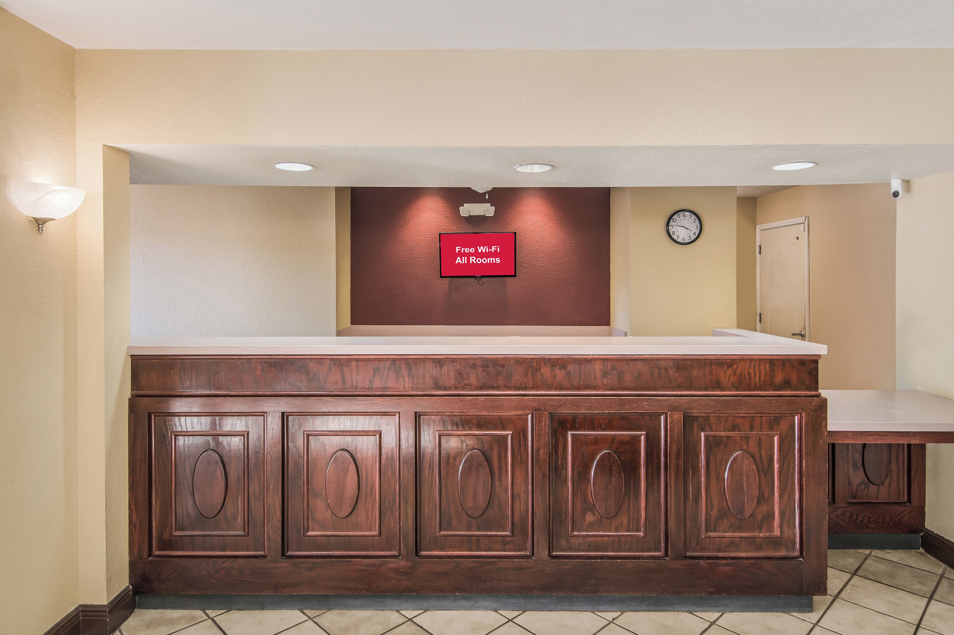 A reception area with a wooden counter, a clock, and a sign indicating free Wi-Fi in all rooms.