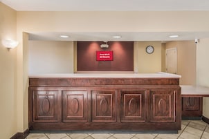 Zona de recepción con mostrador de madera, un reloj y un letrero que indica Wi-Fi gratuito en todas las habitaciones.