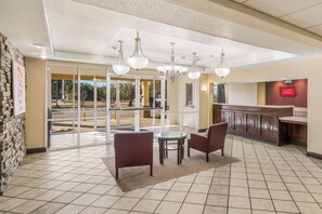 A hotel lobby with a glass partition, a bar area, and a seating arrangement with chairs and a table. - Red Roof Inn & Suites Pensacola East - Milton (Milton)