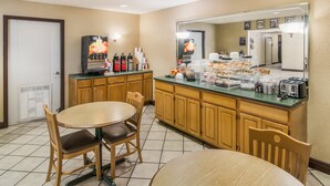 Un espacio para el desayuno con una cafetera, un tostador y diferentes alimentos para el desayuno sobre una encimera.