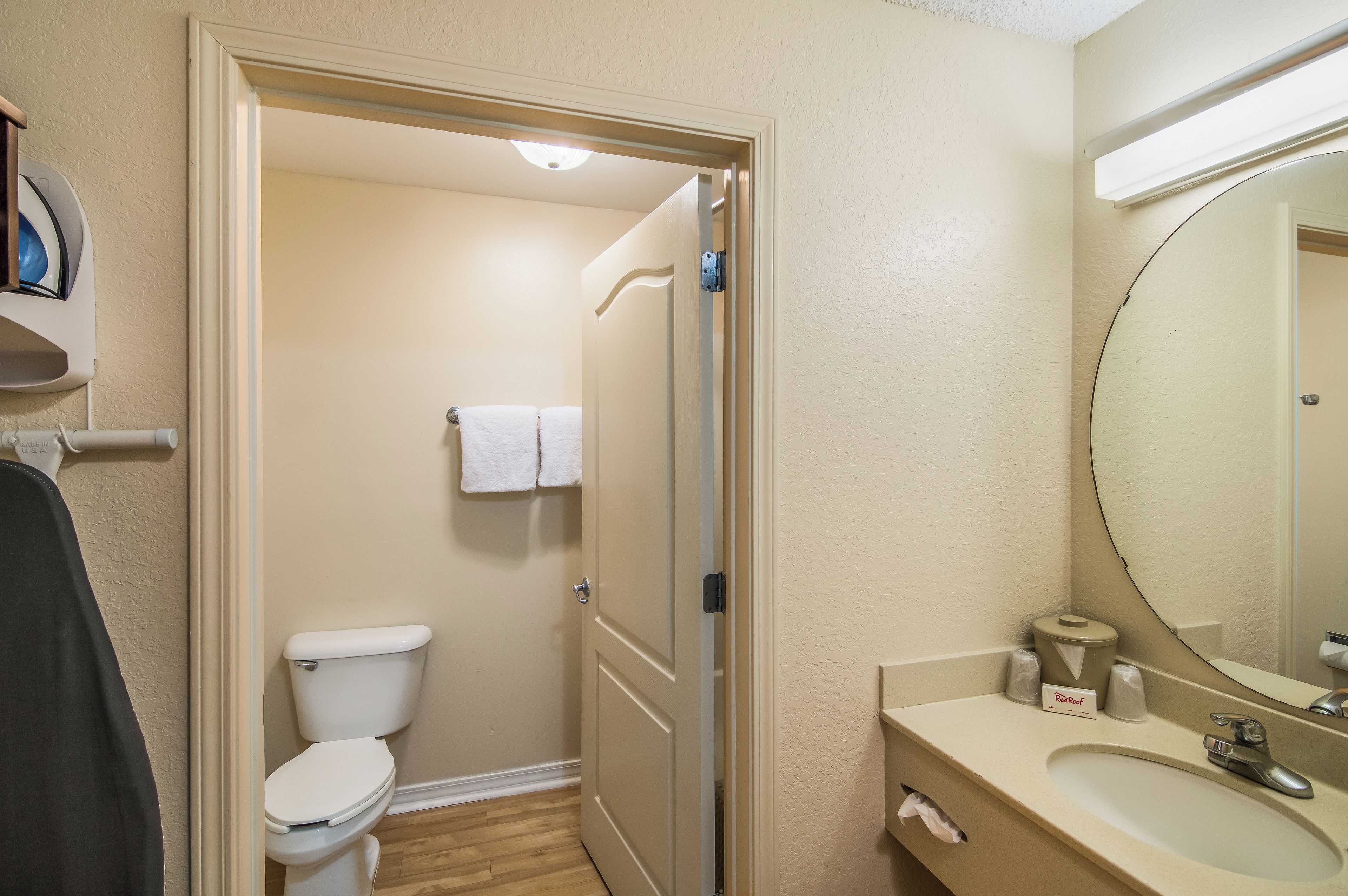 A hotel bathroom with a toilet, a sink, and a mirror.