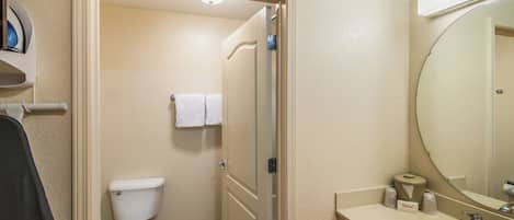 Un baño de hotel con inodoro, lavamanos y espejo.