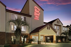 A Red Roof Inn with 4 suites, featuring a brick facade, large windows, and a well-lit entrance. - Red Roof Inn & Suites Pensacola East - Milton (Milton)
