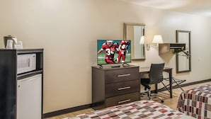 A hotel room with a television, a desk with a chair, a bed with a quilt, a microwave, and a refrigerator. - Red Roof Inn & Suites Pensacola East - Milton (Milton)