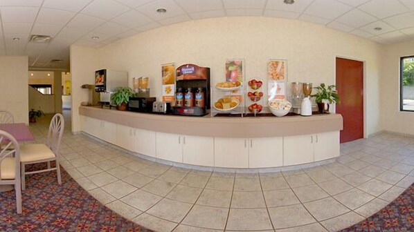 Zona de recepción con mostrador curvo, máquina de café y diversos alimentos a la vista.